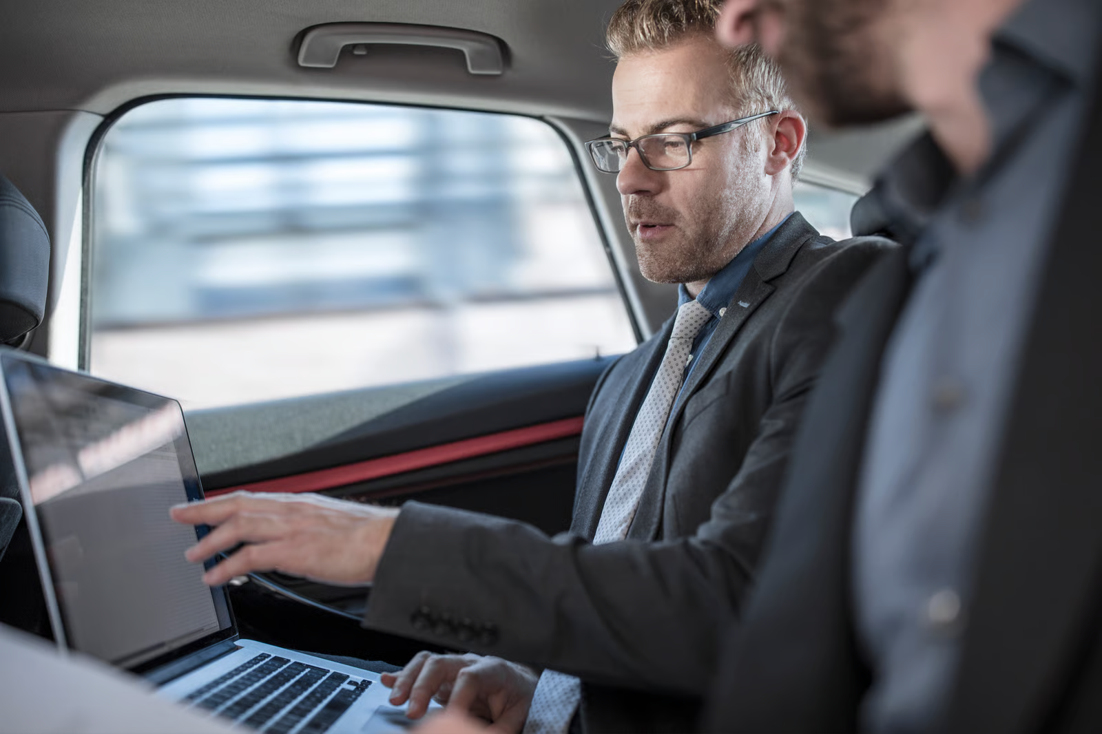 Fahrzeugmanagement — Geschäftstreffen im Auto mit Laptop (Mobiles Büro / Flottenkoordination)